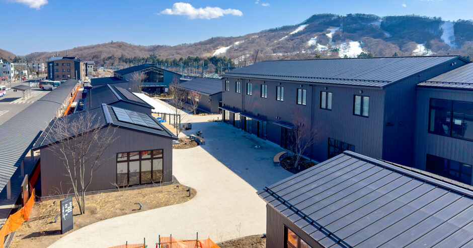 青空と雪山を背景にした、軽井沢T-SITEの黒い外観の全景